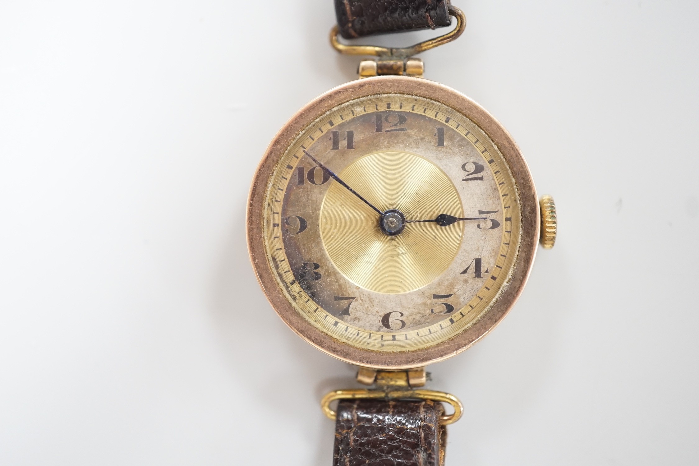 A lady's early 20th century 9ct gold wrist watch, with Arabic dial and RolWatchCo (Wilsdorf & Davis) case, movement unsigned, on associated leather strap, case diameter 26mm, gross weight 17.5 grams.